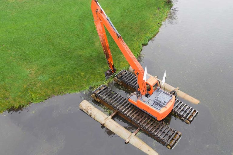 Floating excavator for cleaning ponds, aerial view. Provision of water treatment services.